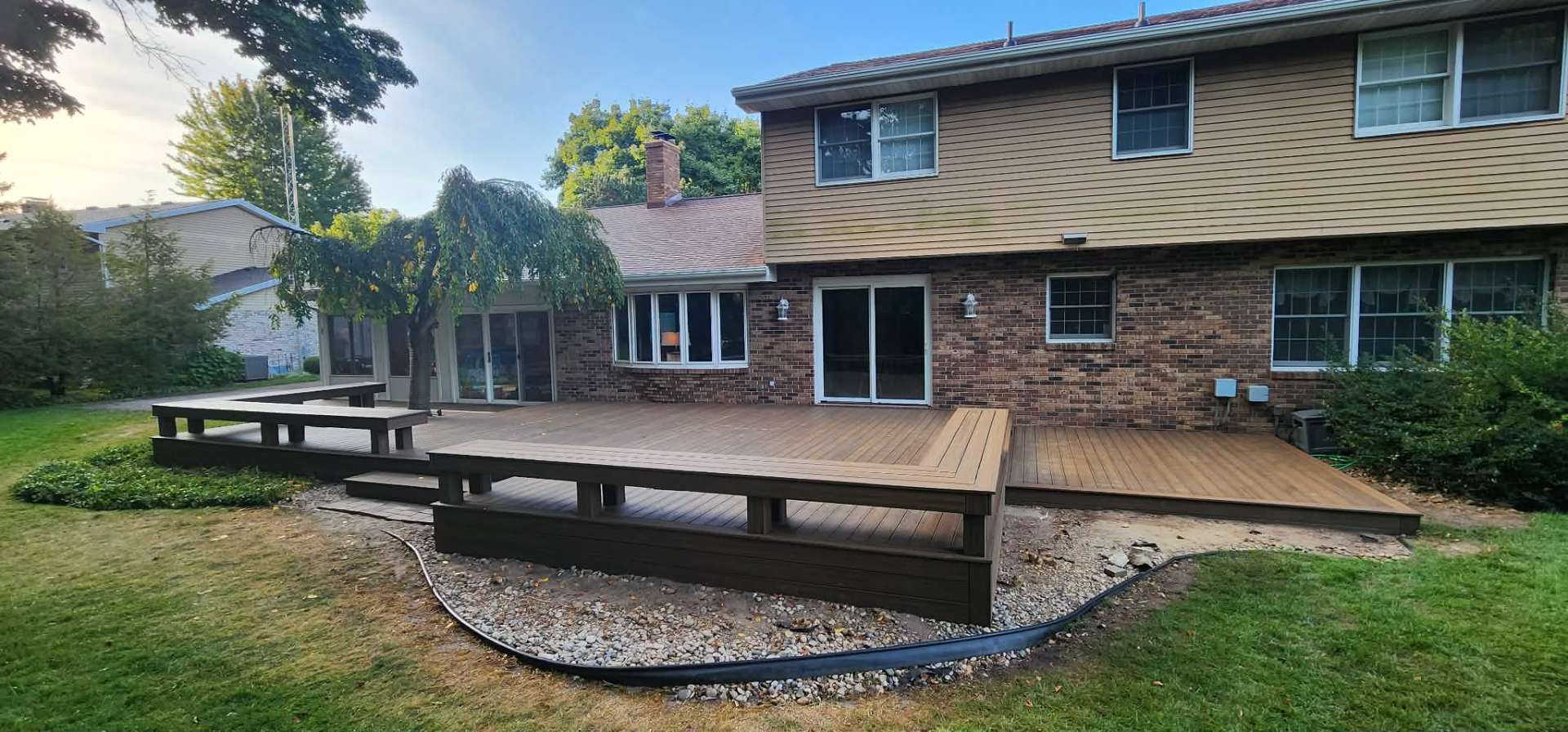 Expansive wraparound composite deck on a hillside lot